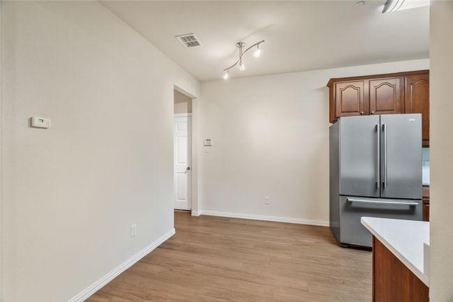 Kitchen with light countertops, visible vents, freestanding refrigerator, light wood-type flooring, and baseboards | Image 12