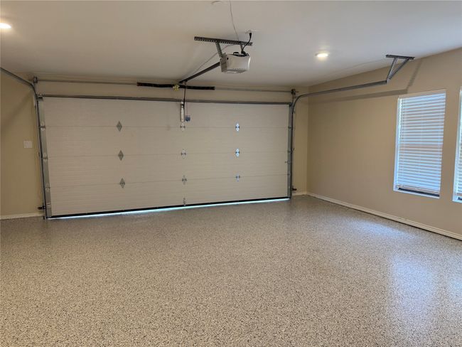 Garage featuring a garage door opener and baseboards | Image 38