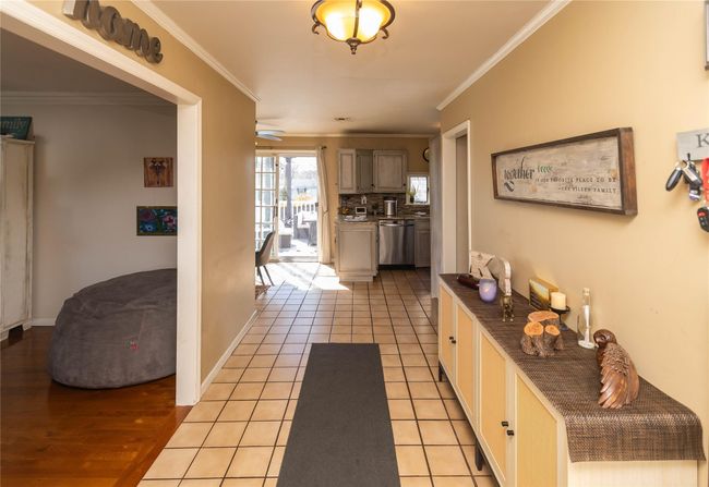 Hallway with baseboards, light tile patterned floors, and crown molding | Image 13