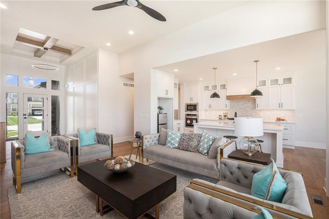 Living room featuring light wood-type flooring, coffered ceiling, ceiling fan, recessed lighting, and beam ceiling | Image 7