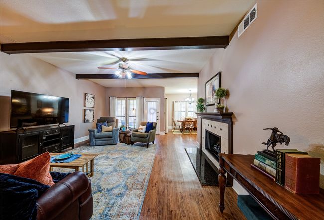Living room featuring beam ceiling, a ceiling fan, wood finished floors, and a chandelier | Image 6