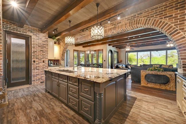 Kitchen with a sink, brick wall, and dark wood-type flooring | Image 19