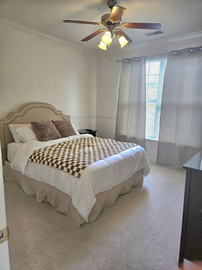 The bedroom is flooded with light from the large window and also boasts crown molding, chair rail, and an overhead light/fan. | Image 9