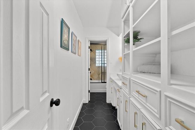 Hallway bath with built-in linen cabinetry and sleek black hex tile flooring. | Image 32