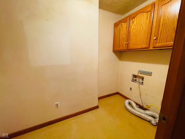 laundry area with cabinet space, light carpet, hookup for a washing machine, a textured ceiling, and baseboards | Image 25