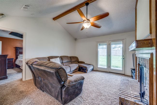 Carpeted living area with a ceiling fan, a textured ceiling, and a fireplace with raised hearth | Image 5