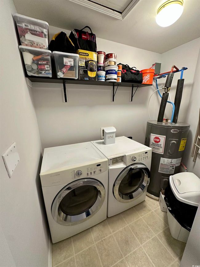 Laundry room featuring water heater, washer and clothes dryer, and light tile patterned floors | Image 24