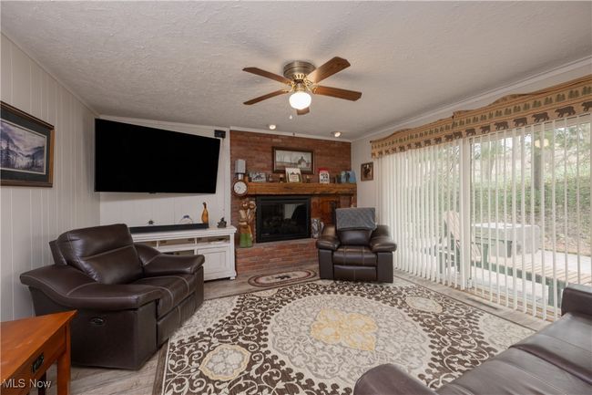 Living room featuring ornamental molding, a textured ceiling, a fireplace, and ceiling fan | Image 18