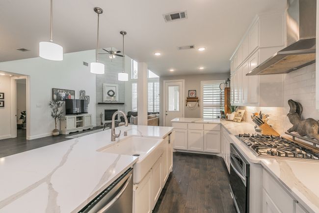 Kitchen featuring wall chimney exhaust hood, ceiling fan, dark wood-type flooring, lofted ceiling, and a fireplace | Image 4
