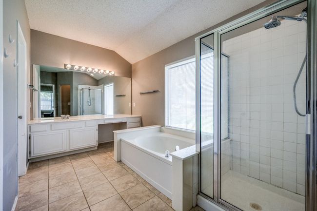 Bathroom featuring a shower stall, vanity, a garden tub, vaulted ceiling, and tile patterned floors | Image 16