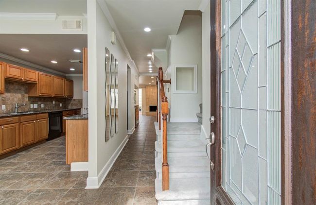 Step into elegance with this inviting entryway, featuring a stylish glass door and a glimpse of the open-concept kitchen and living space. | Image 6