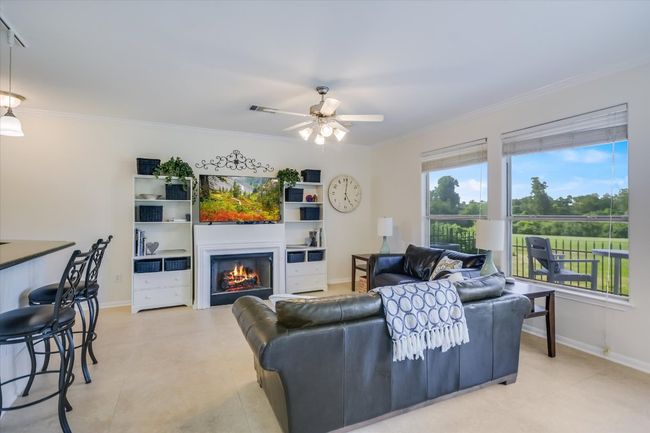 Living area with a lit fireplace, ornamental molding, and ceiling fan | Image 4
