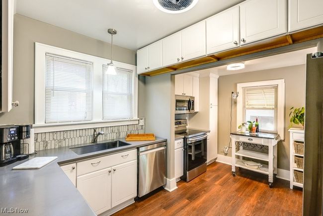 Kitchen featuring a sink, pendant lighting, stainless steel appliances, white cabinetry, and dark wood-style floors | Image 14