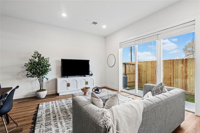 This stylish living room features warm LVP flooring, a neutral color palette, and an open-concept layout perfect for relaxation and entertaining. | Image 9