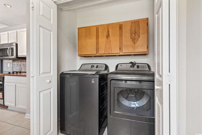Laundry area featuring cabinet space, light tile patterned floors, washer and dryer, wine cooler, and recessed lighting | Image 15
