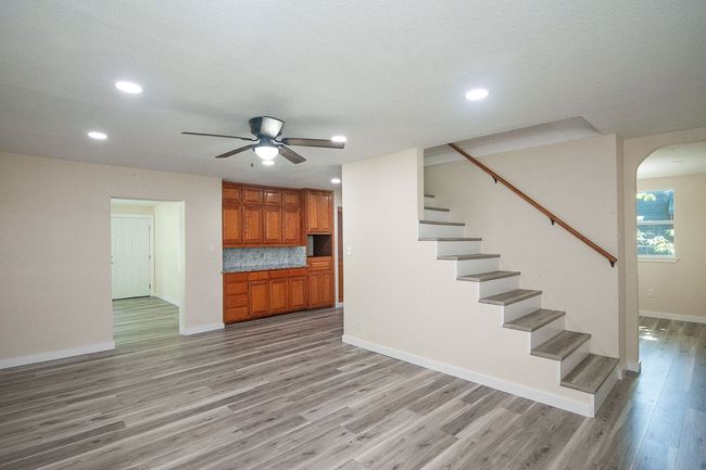 Unfurnished living room with light wood-style floors, stairway, ceiling fan, recessed lighting, and arched walkways | Image 8