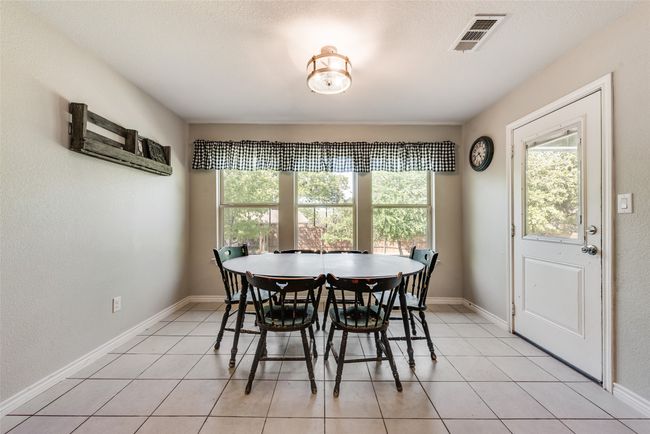 Dining space with a healthy amount of sunlight, light tile patterned flooring, baseboards, and visible vents | Image 11