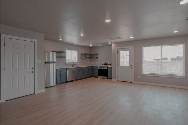 Kitchen with stainless steel appliances, open shelves, light countertops, light wood-style floors, and recessed lighting | Image 7