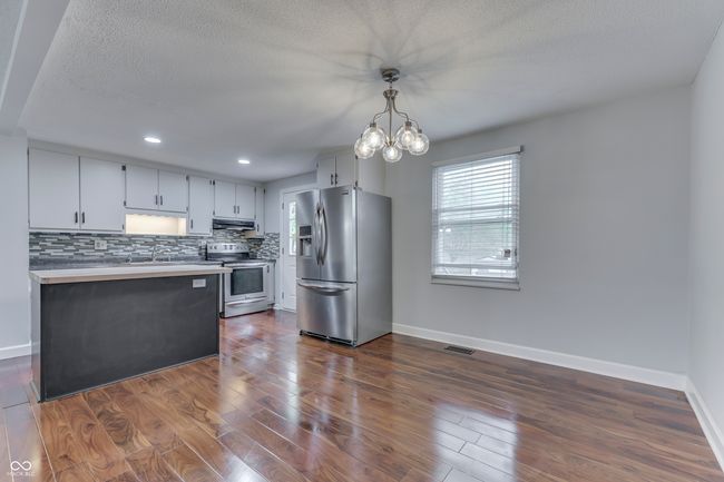 kitchen with decorative backsplash, stainless steel appliances, under cabinet range hood, baseboards, and visible vents | Image 10