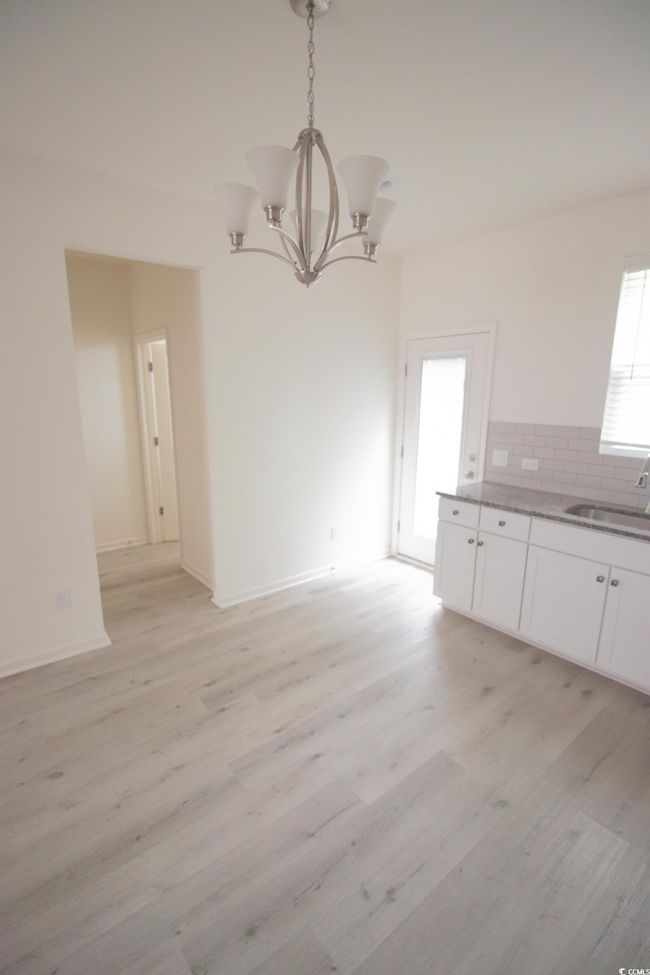 Unfurnished dining area with a sink, a chandelier, light wood-type flooring, and baseboards | Image 5