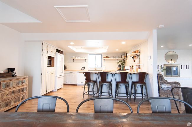 Kitchen with open shelves, light wood-style flooring, white appliances, a kitchen breakfast bar, and light countertops | Image 4