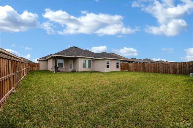 Back of house with a yard, a shingled roof, a fenced backyard, and stucco siding | Image 19