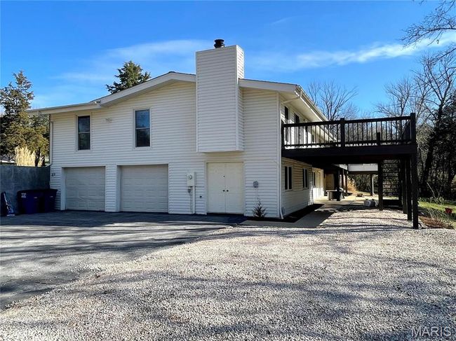 View of property exterior with a chimney, driveway, a wooden deck, and a garage | Image 31