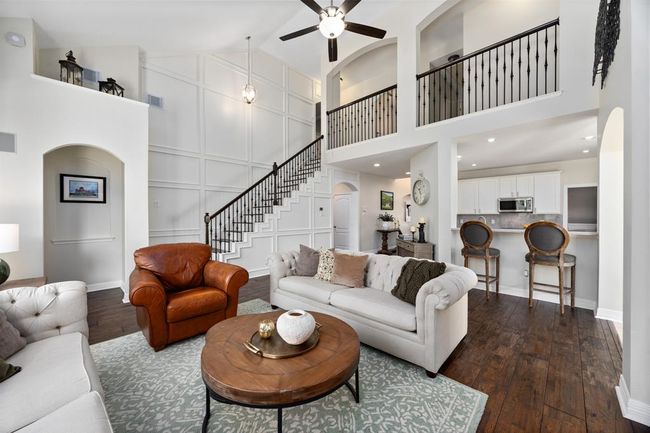 The open floorplan features soaring ceilings, custom built-ins, and a stunning custom millwork wall along the staircase. | Image 7