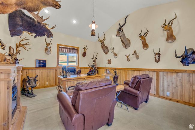 Trophy/bonus room built next to garage. Carpeted room featuring a wainscoted wall, vaulted ceiling, a high end fireplace, wood walls, and recessed lighting | Image 44