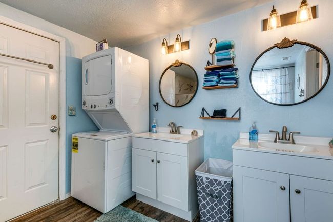 Laundry area with dark wood-style floors, stacked washer and clothes dryer, a sink, and a textured ceiling | Image 15