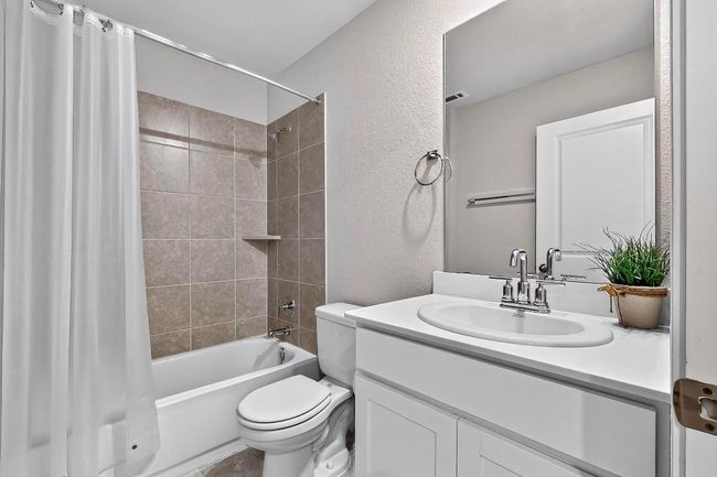 Bathroom featuring shower / bath combo with shower curtain, a textured wall, and vanity | Image 28