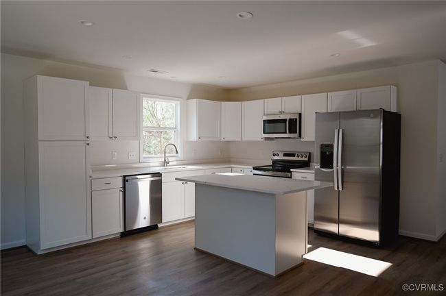 Kitchen featuring white cabinetry, dark hardwood / wood-style flooring, a center island, and appliances with stainless steel finishes | Image 4