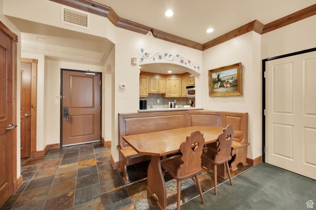 Dining area with baseboards, ornamental molding, visible vents, and stone tile floors | Image 15