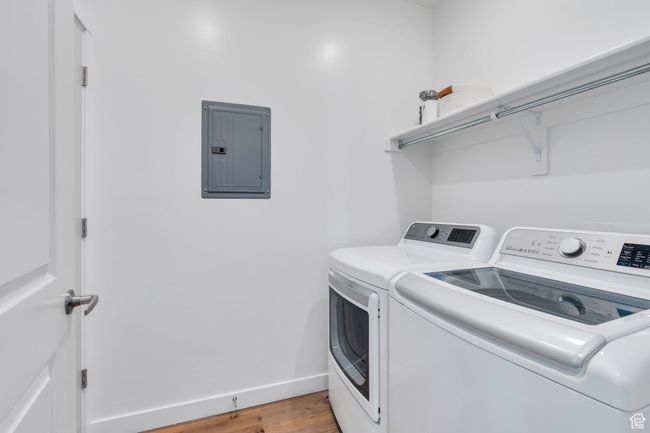Washroom featuring laundry area, light wood-style flooring, electric panel, baseboards, and washing machine and dryer | Image 14