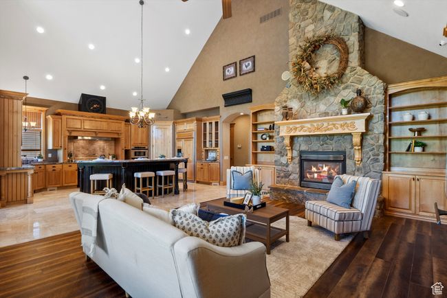 Living room with high vaulted ceiling, a chandelier, a stone fireplace, arched walkways, and recessed lighting | Image 26