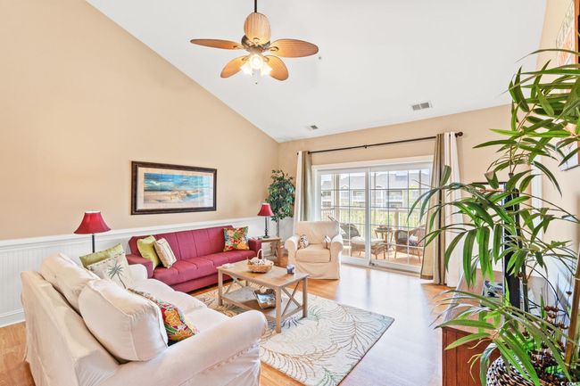 Living room with light wood-style floors, high vaulted ceiling, ceiling fan, and a wainscoted wall | Image 14
