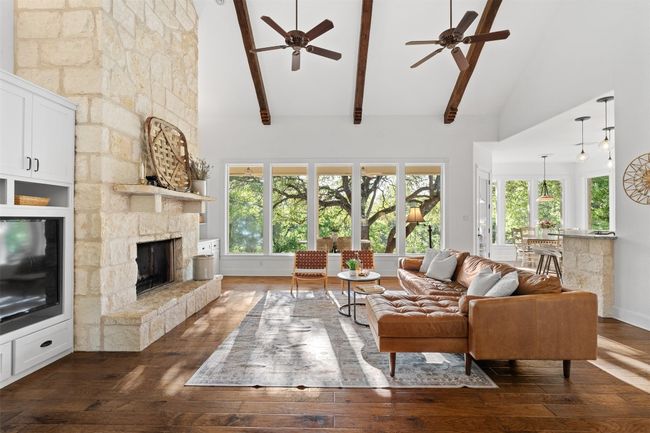 Living room featuring high vaulted ceiling, a fireplace, a ceiling fan, and a wealth of natural light | Image 7