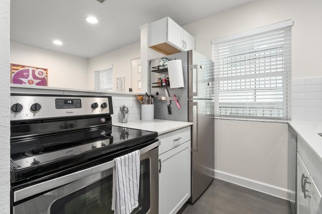 Kitchen with stainless steel appliances, light countertops, white cabinets, recessed lighting, and tasteful backsplash | Image 7