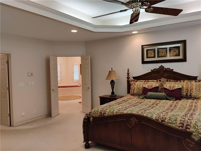 Bedroom featuring recessed lighting, a raised ceiling, a ceiling fan, light carpet, and connected Primary bathroom | Image 46