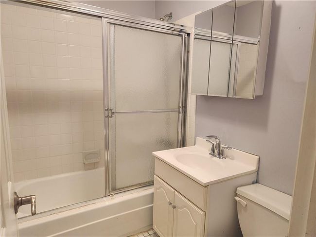 Full bathroom with toilet, bath / shower combo with glass door, and vanity | Image 12