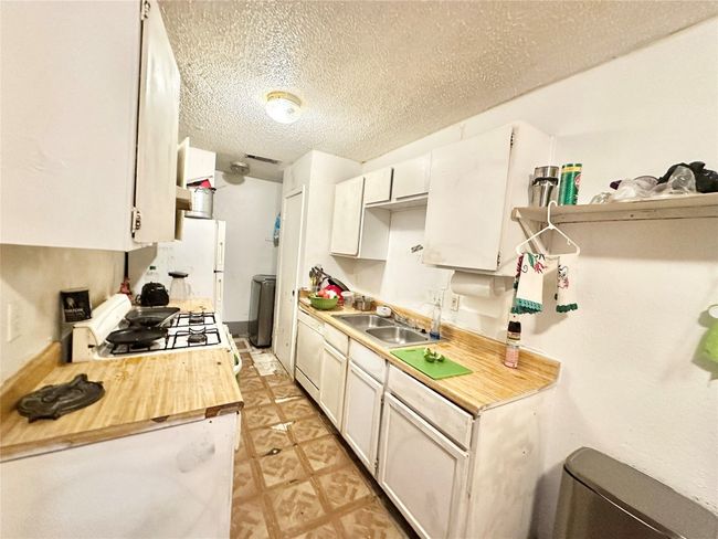 Kitchen featuring a sink, a textured ceiling, range, white cabinets, and butcher block countertops | Image 34