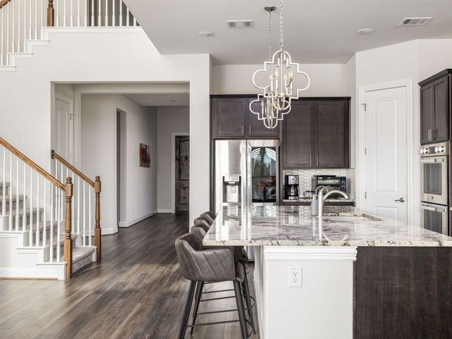 Kitchen featuring dark wood-style floors, visible vents, a sink, and stainless steel appliances | Image 5