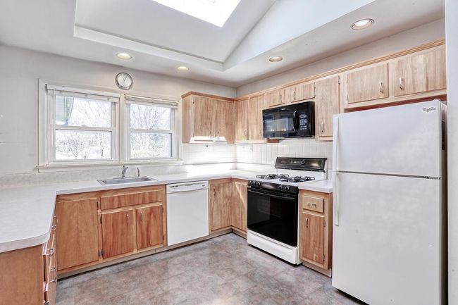 Kitchen with recessed lighting, light countertops, backsplash, a sink, and white appliances | Image 9