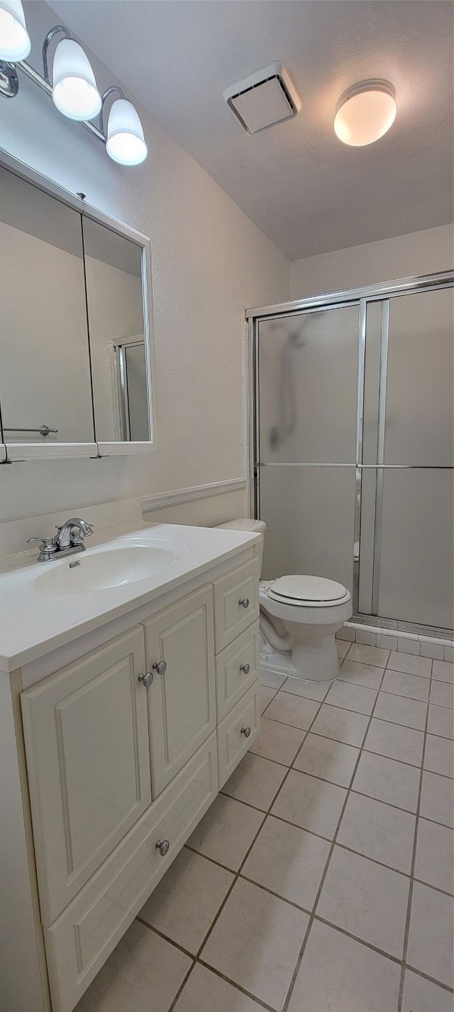 Full bathroom featuring tile patterned floors, vanity, toilet, and a stall shower | Image 14