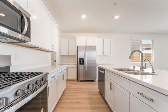 Kitchen with stainless steel appliances, white cabinets, light wood-type flooring, and recessed lighting | Image 13