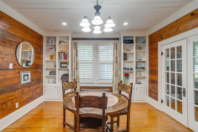 Dining space featuring wooden walls, a chandelier, light wood-type flooring, ornamental molding, and wooden ceiling | Image 21