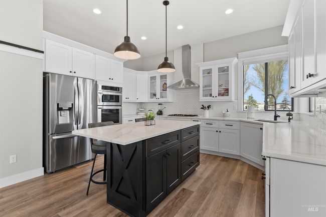 Kitchen with appliances with stainless steel finishes, wall chimney range hood, white cabinetry, dark cabinets, and recessed lighting | Image 20