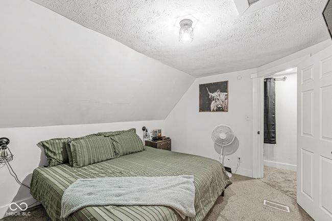 carpeted bedroom featuring vaulted ceiling, baseboards, and a textured ceiling | Image 19