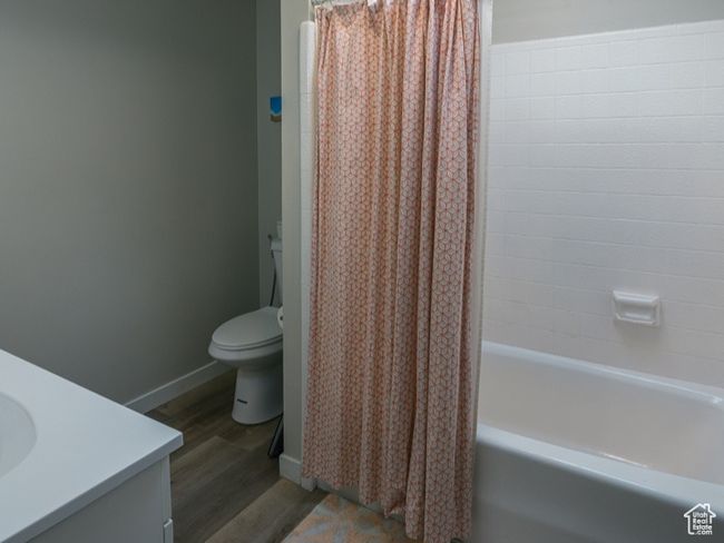 Bathroom featuring visible vents, toilet, shower / bath combo with shower curtain, wood finished floors, and a skylight | Image 6