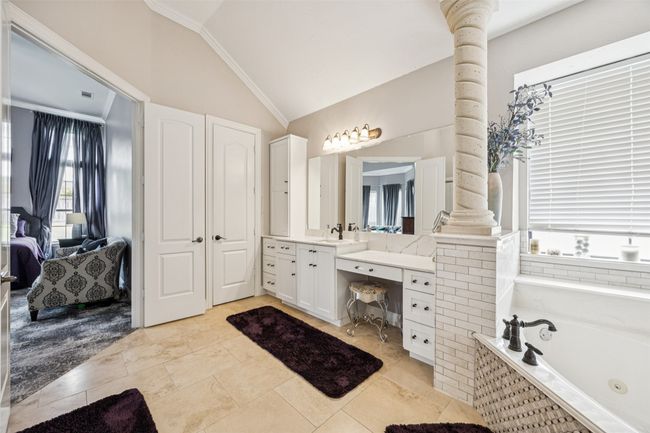 Ensuite bathroom featuring ornate columns, plenty of natural light, vaulted ceiling, vanity, and a whirlpool tub | Image 25